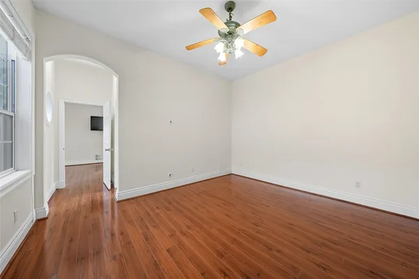 a view of an empty room with a window and wooden floor