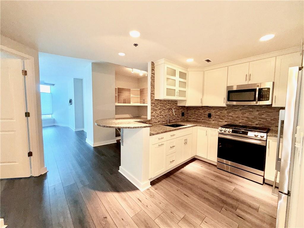 3338 Peachtree Road Northeast, Unit 1905 Atlanta, GA 30326 - Photo 2 of 25 a large kitchen with cabinets wooden floor and stainless steel appliances