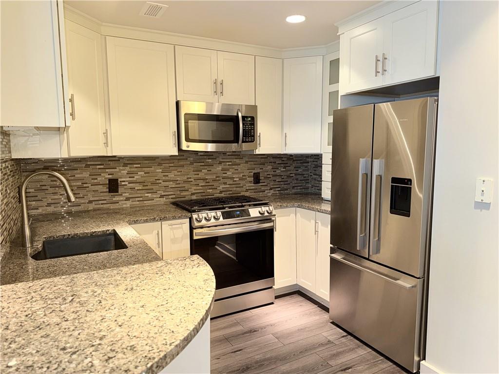 3338 Peachtree Road Northeast, Unit 1905 Atlanta, GA 30326 - Photo 3 of 25 a kitchen with stainless steel appliances granite countertop a refrigerator a stove and a sink with wooden floor