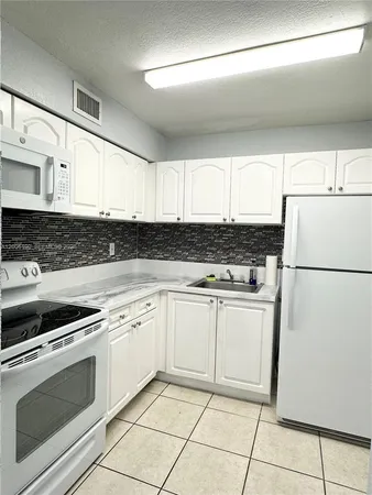a kitchen with granite countertop white cabinets and white appliances