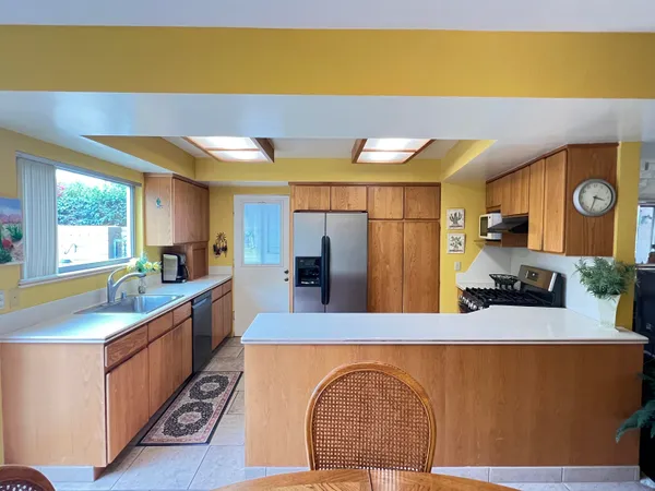 a kitchen with stainless steel appliances granite countertop a sink a stove top oven a chimney wooden floor and a dining table with painted walls