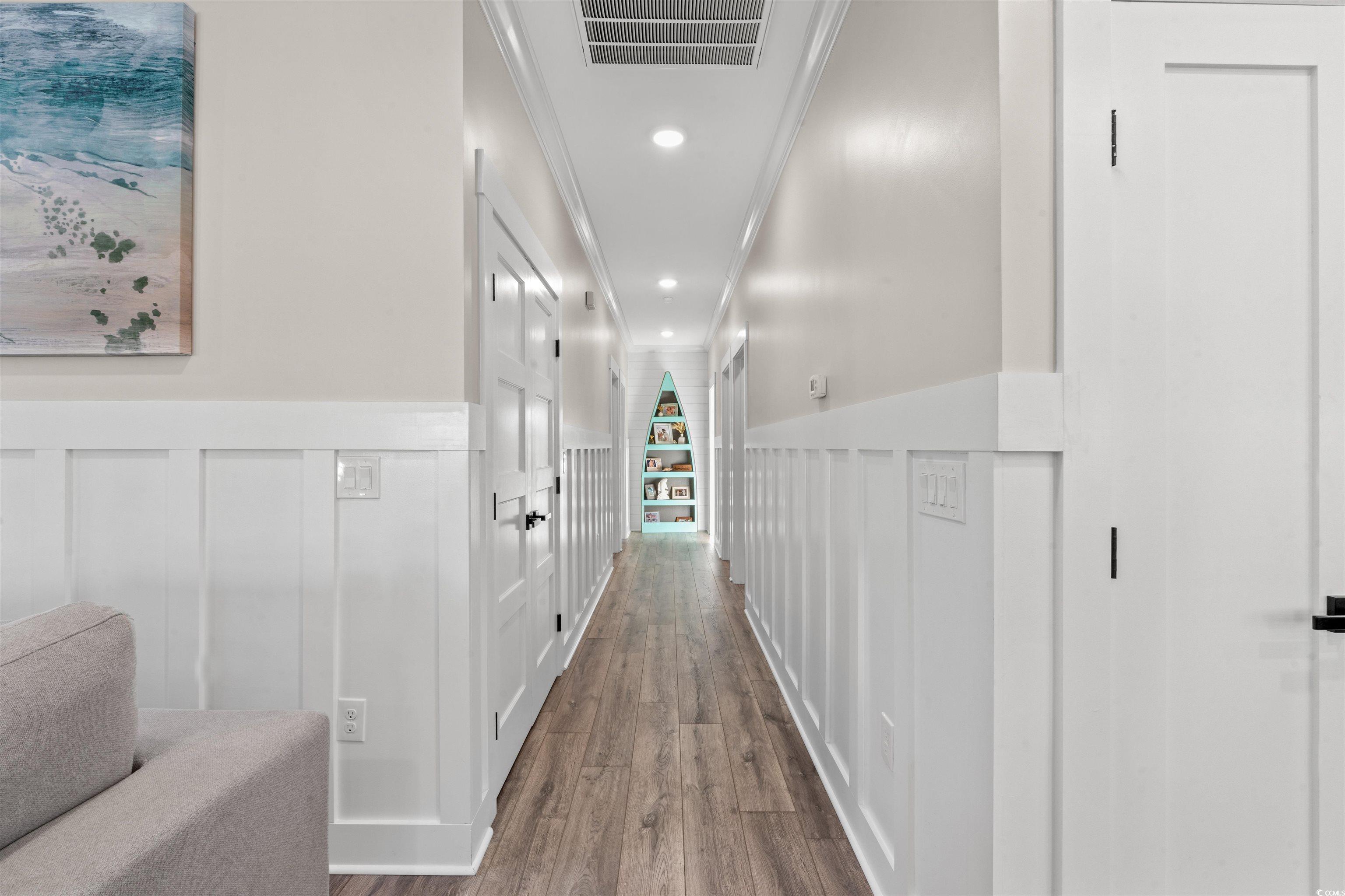 355 Oak Avenue Murrells Inlet, SC 29576 - Photo 17 of 34 Corridor with wood finished floors, visible vents, a decorative wall, crown molding, and wainscoting