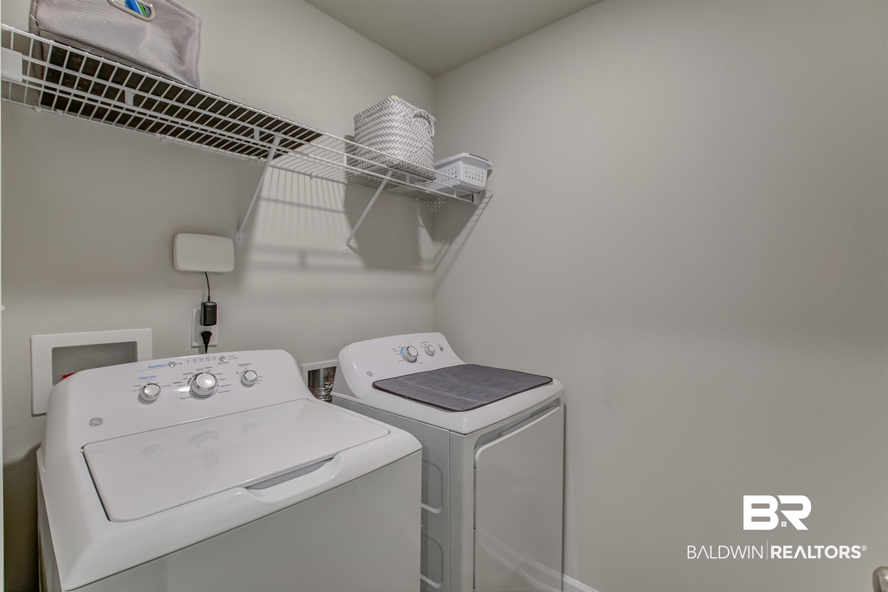 8033 Irwin Loop Daphne, AL 36526 - Photo 33 of 38 Dedicated laundry area with light gray walls, white wire shelving, and appliance hookups