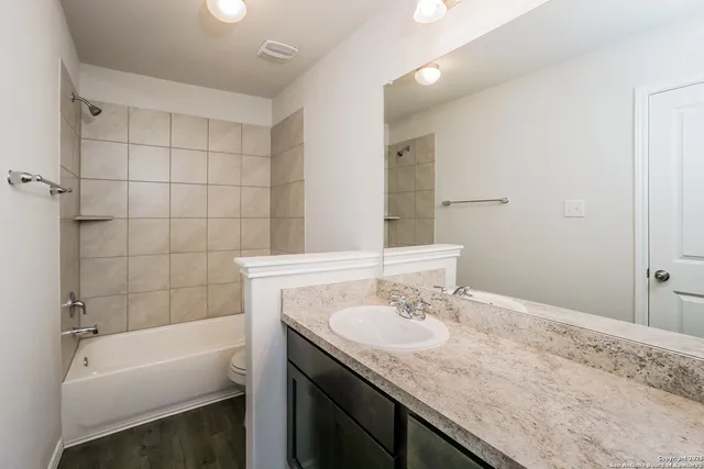 a bathroom with a granite countertop tub sink and mirror