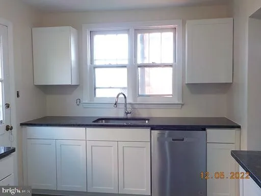 a kitchen with granite countertop white cabinets and a window