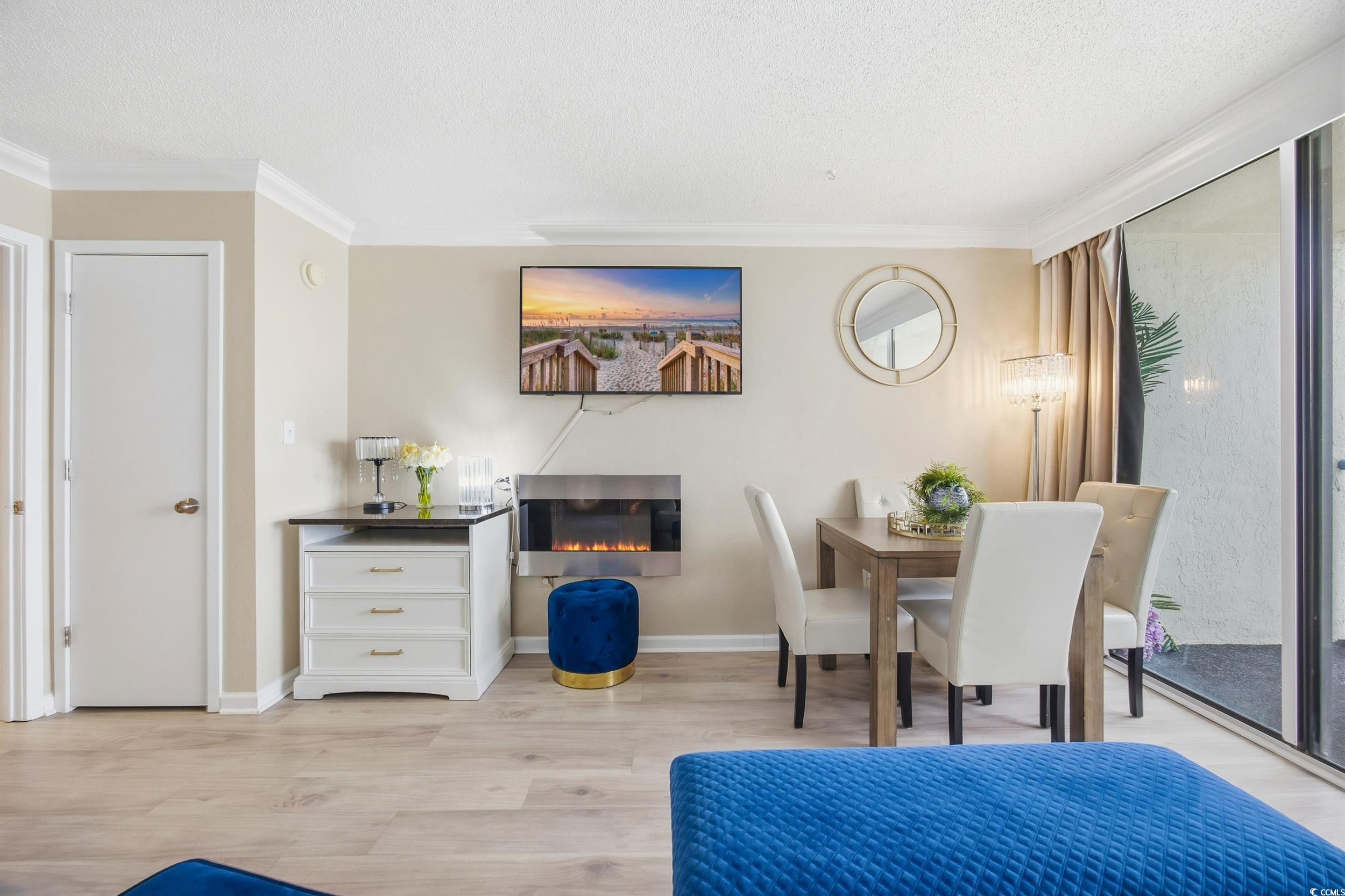 1105 South Ocean Boulevard, Unit 932 Myrtle Beach, SC 29577 - Photo 24 of 32 Dining area with ornamental molding, light wood-type flooring, a textured ceiling, and a glass covered fireplace