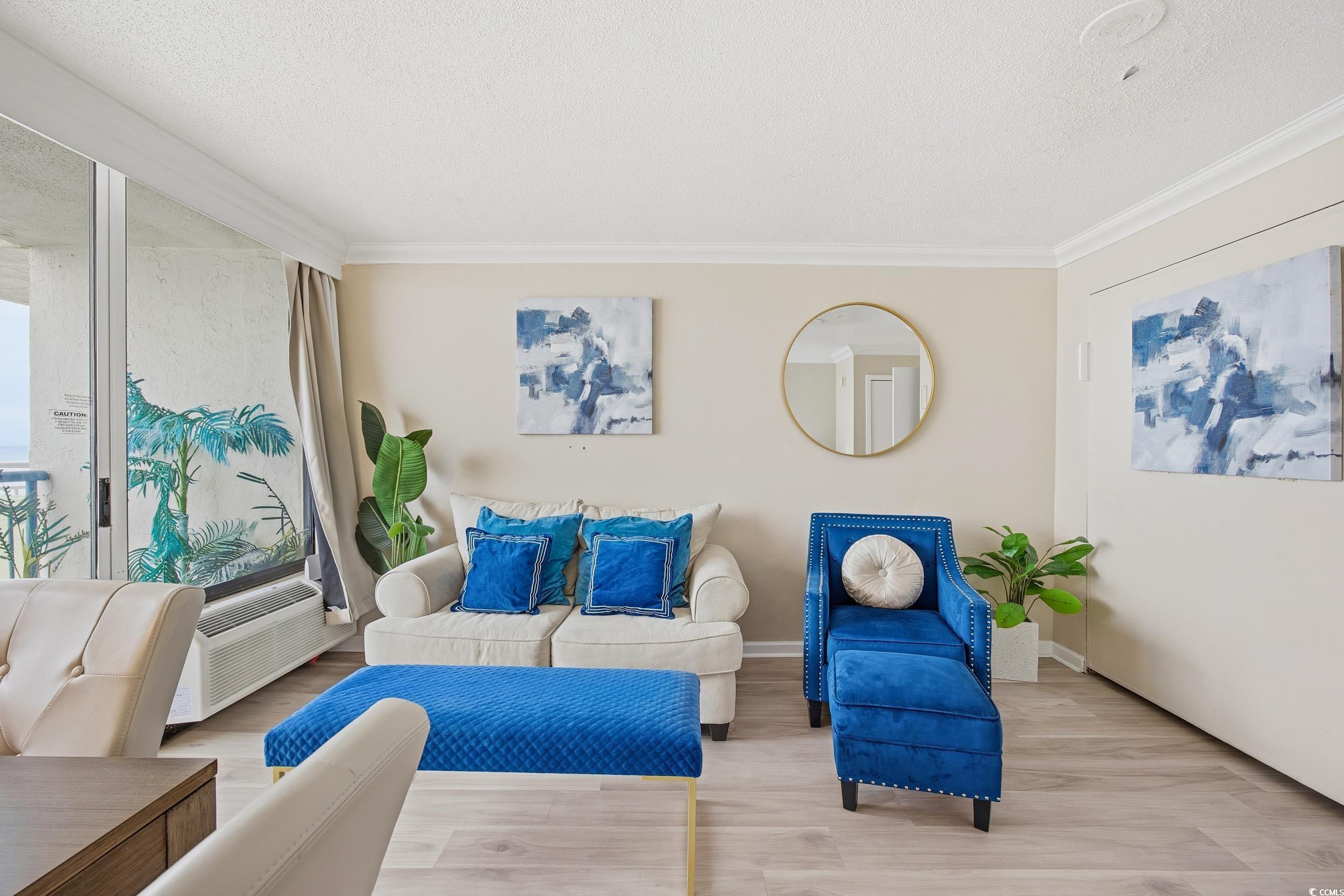 1105 South Ocean Boulevard, Unit 932 Myrtle Beach, SC 29577 - Photo 26 of 32 Living room featuring wood finished floors, a textured ceiling, ornamental molding, and an AC wall unit