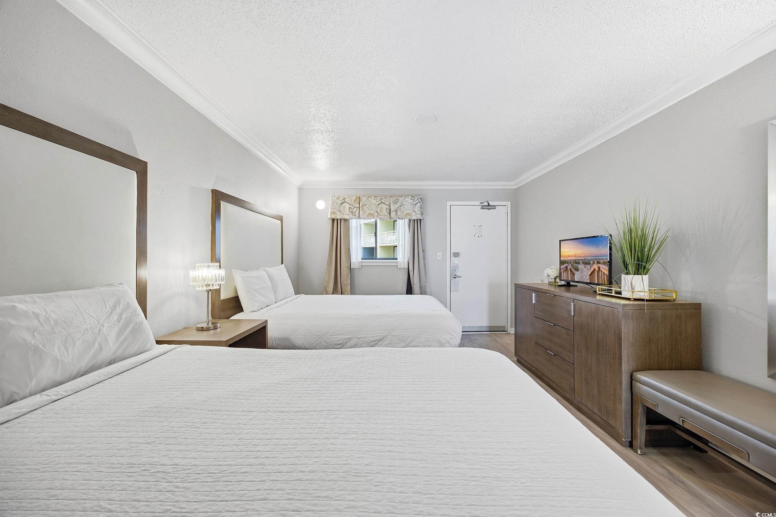 1105 South Ocean Boulevard, Unit 932 Myrtle Beach, SC 29577 - Photo 10 of 32 Bedroom featuring ornamental molding, light wood-type flooring, and a textured ceiling