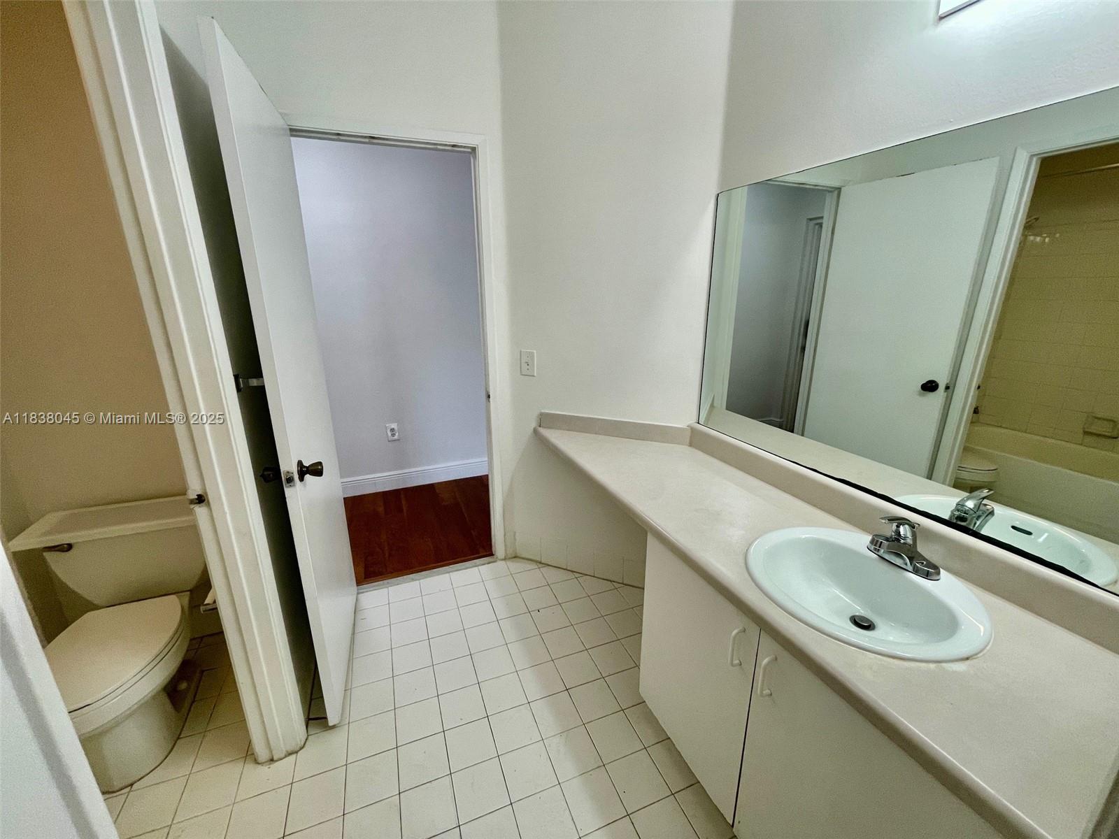 6984 Southwest 39th Street, Unit H202 Davie, FL 33314 - Photo 12 of 17 a bathroom with a sink a toilet and a mirror