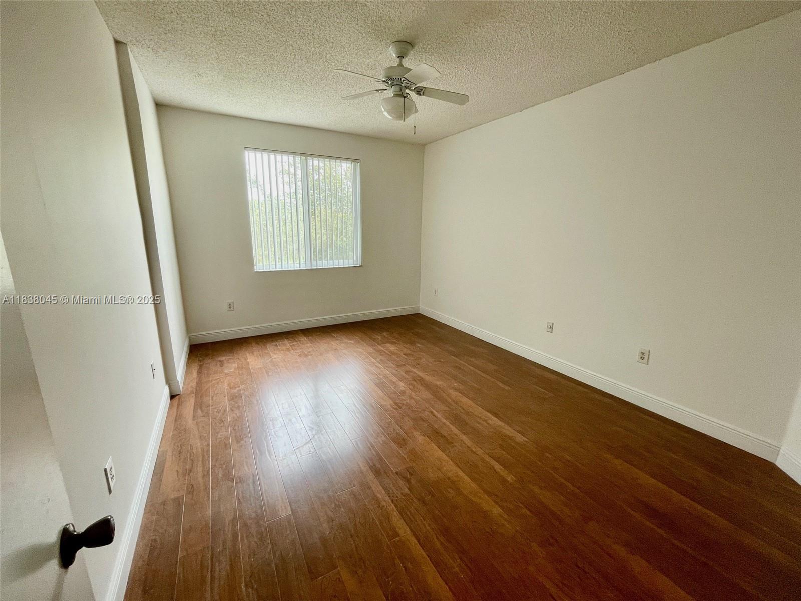 6984 Southwest 39th Street, Unit H202 Davie, FL 33314 - Photo 8 of 17 an empty room with wooden floor chandelier fan and windows