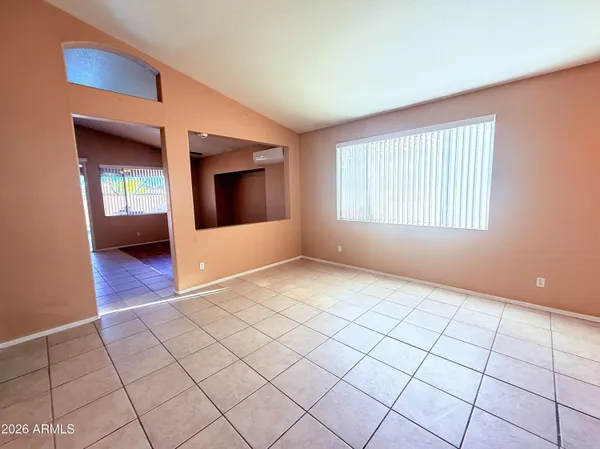 a view of an empty room with window and a kitchen