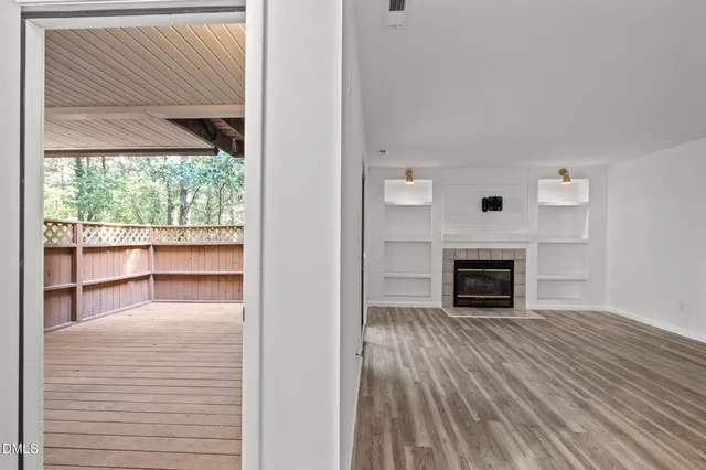 a view of a livingroom with wooden floor a fireplace and windows