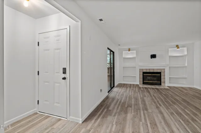 a view of a livingroom with a fireplace wooden floor and window