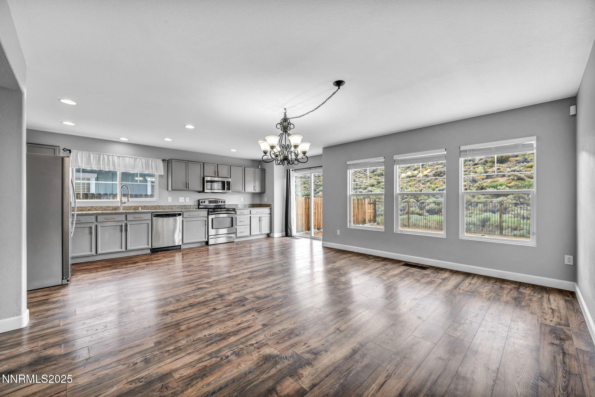 7644 Corso Street Reno, NV 89506 - Photo 41 of 54 a view of an empty room with wooden floor and a kitchen