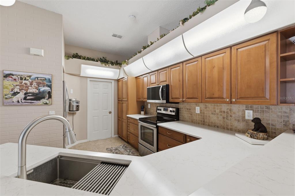 7442 Aloe Drive Spring Hill, FL 34607 - Photo 16 of 59 a kitchen with stainless steel appliances granite countertop a sink a stove top oven a counter space and cabinets