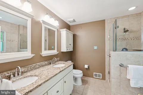 a bathroom with a granite countertop sink mirror vanity and toilet
