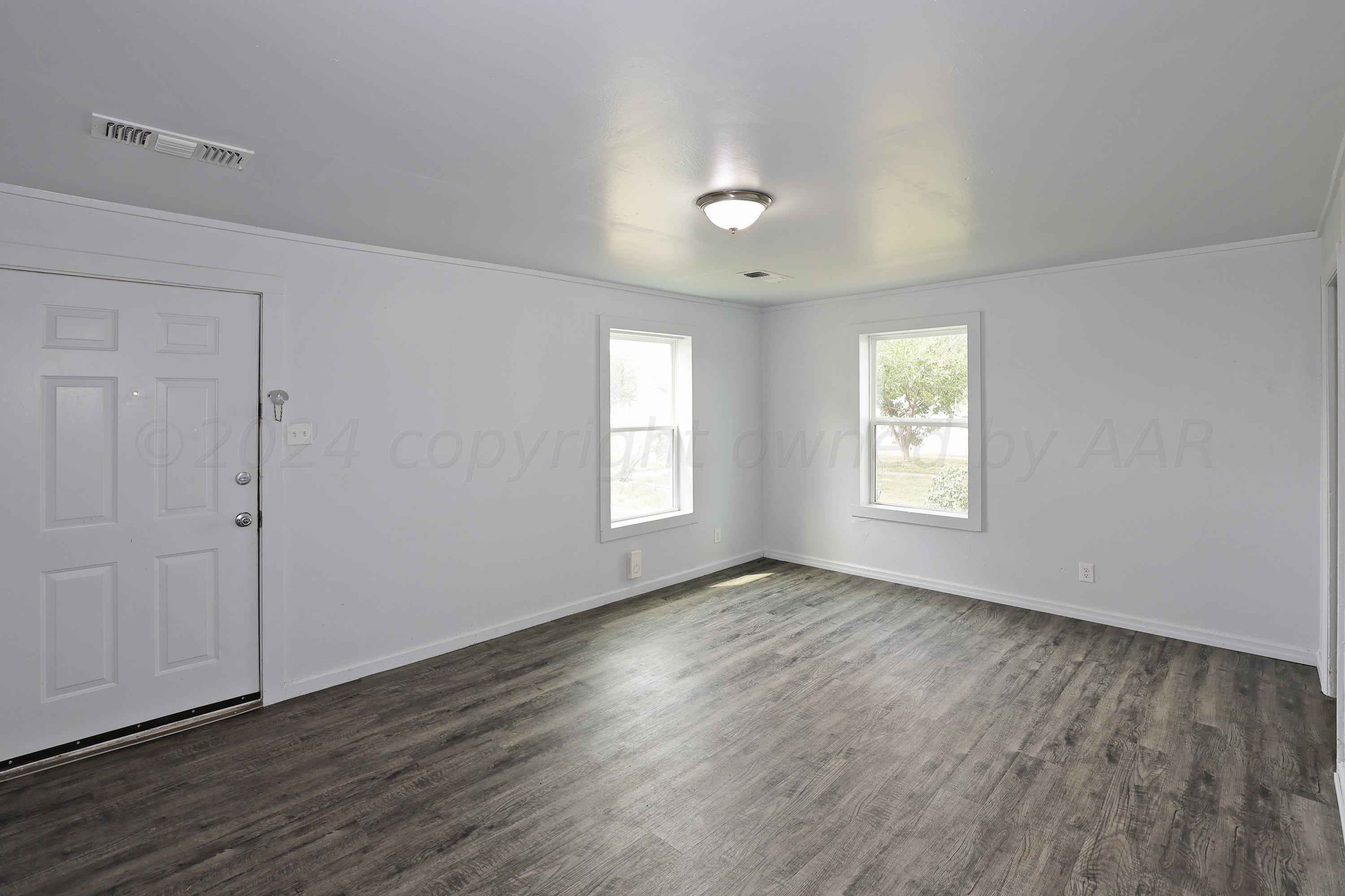 3703 South Monroe Street Amarillo, TX 79110 - Photo 3 of 13 an empty room with wooden floor and windows