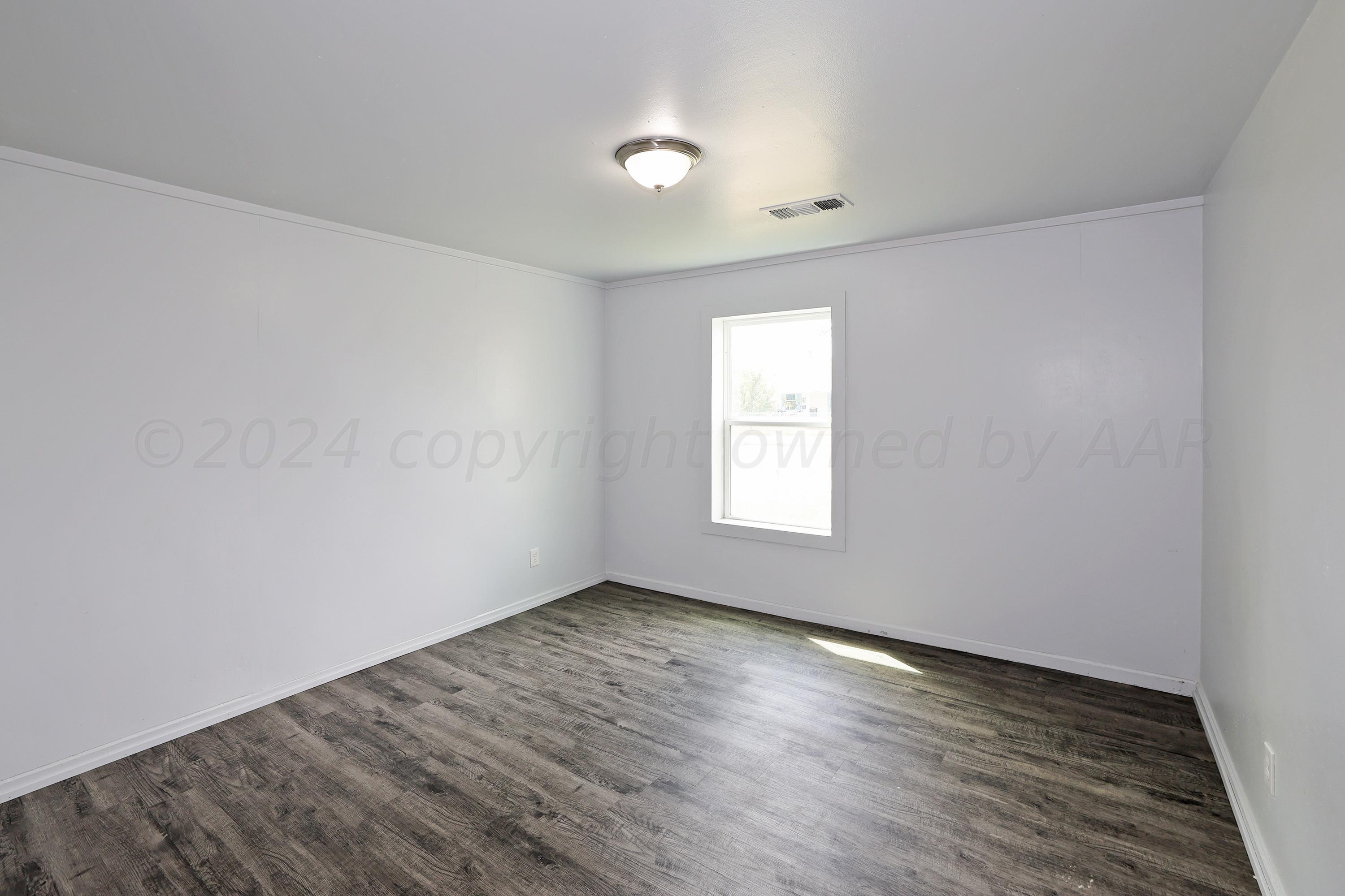 3703 South Monroe Street Amarillo, TX 79110 - Photo 9 of 13 an empty room with wooden floor and windows