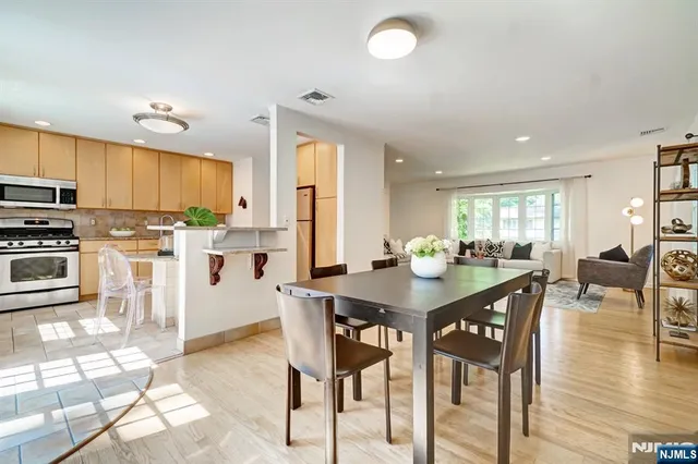 a kitchen with stainless steel appliances kitchen island granite countertop a table chairs and a refrigerator