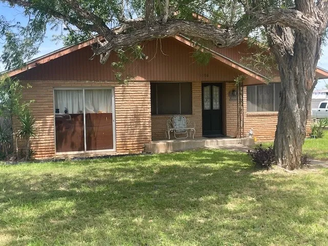 a view of a house with backyard and a tree