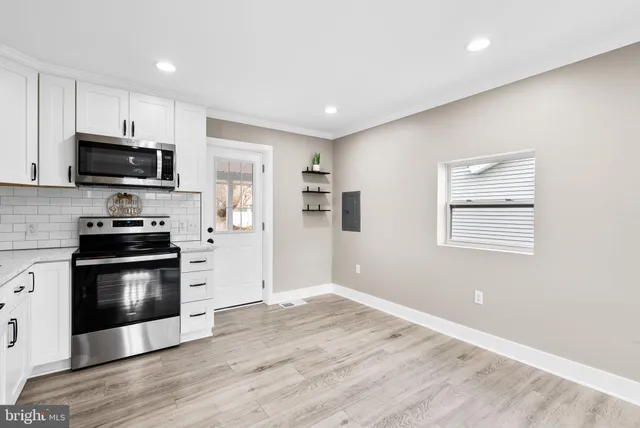 a kitchen with stainless steel appliances a stove a microwave and white cabinets