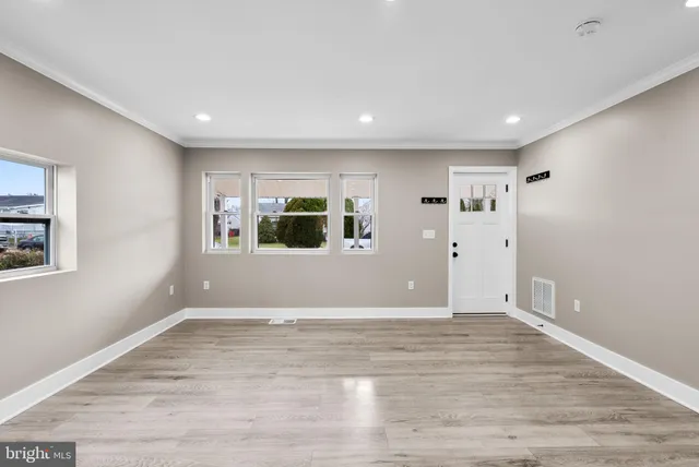 a view of empty room with wooden floor and windows