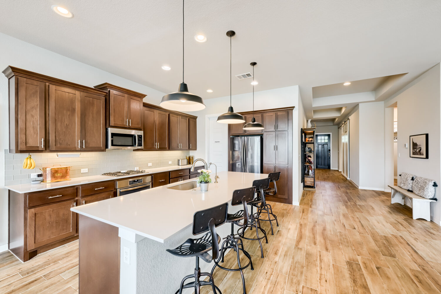 621 Rancho Sienna Loop Georgetown, TX 78628 - Photo 10 of 28 A streamlined open-concept kitchen features dark wood cabinetry, light countertops, and a central island with pendant lighting.