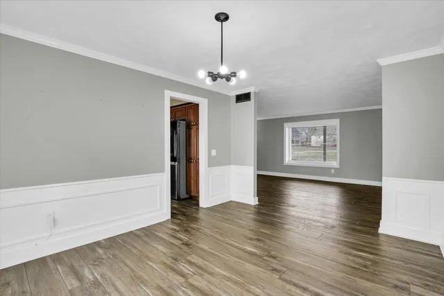 a view of a room with wooden floor chandelier and windows