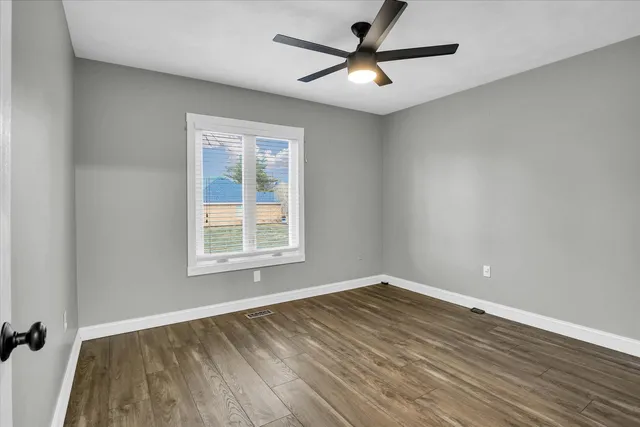 an empty room with wooden floor closet and windows