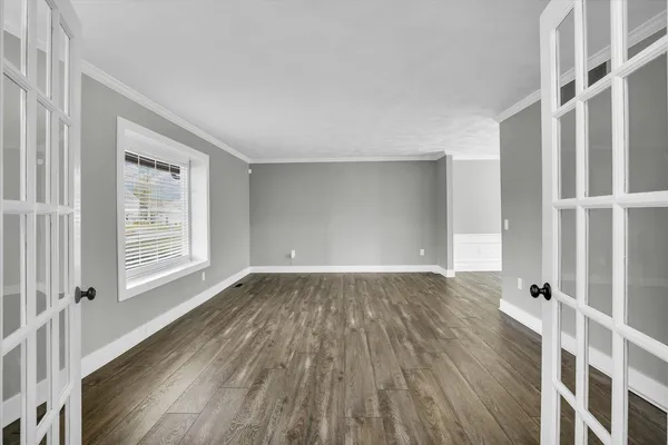 a view of a room with wooden floor chandelier and windows