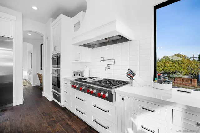a kitchen with stainless steel appliances granite countertop a sink a stove and chairs