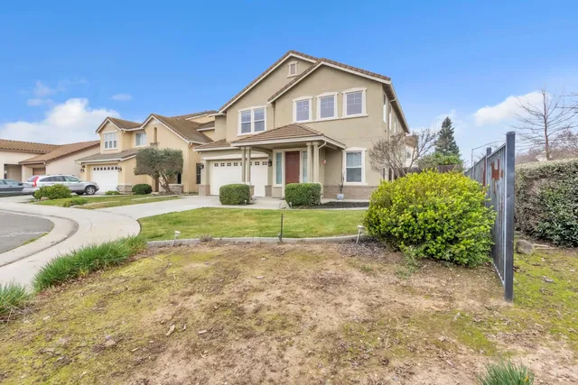 a front view of a house with a yard and potted plants