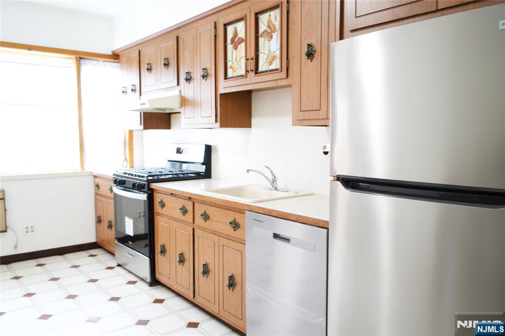 133 Oak Street, Unit 1 Weehawken, NJ 07086 - Photo 3 of 9 a kitchen with stainless steel appliances a refrigerator sink and cabinets