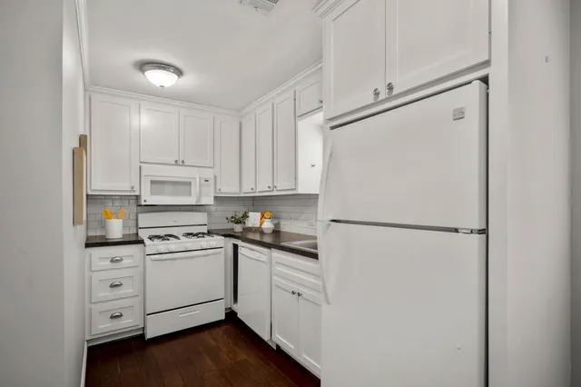 a kitchen with white cabinets and white appliances