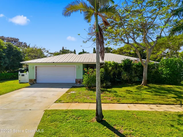 a view of a white house with a small yard and a large tree