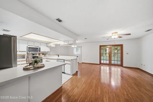 a kitchen with stainless steel appliances granite countertop a stove top oven a sink dishwasher and a refrigerator with wooden floor