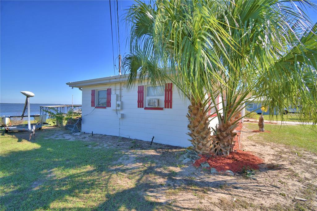 105 Maxcy Lane Frostproof, FL 33843 - Photo 41 of 49 a backyard of a house with table and chairs a barbeque with potted plants and a large tree