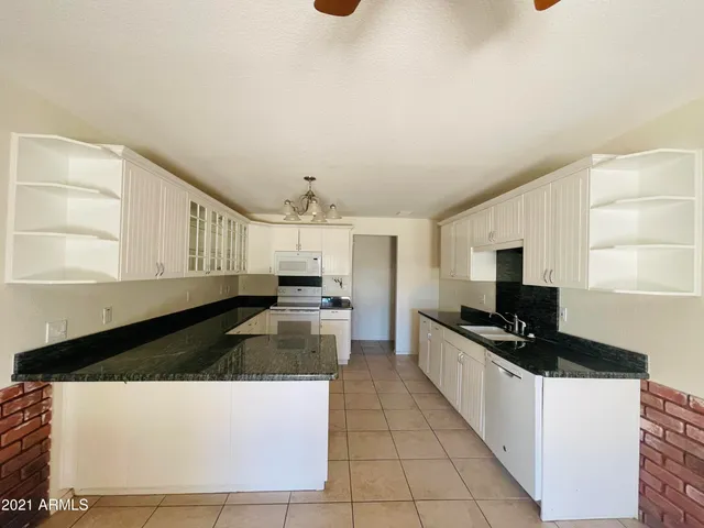 a kitchen with granite countertop a sink a stove top oven a counter space and cabinets