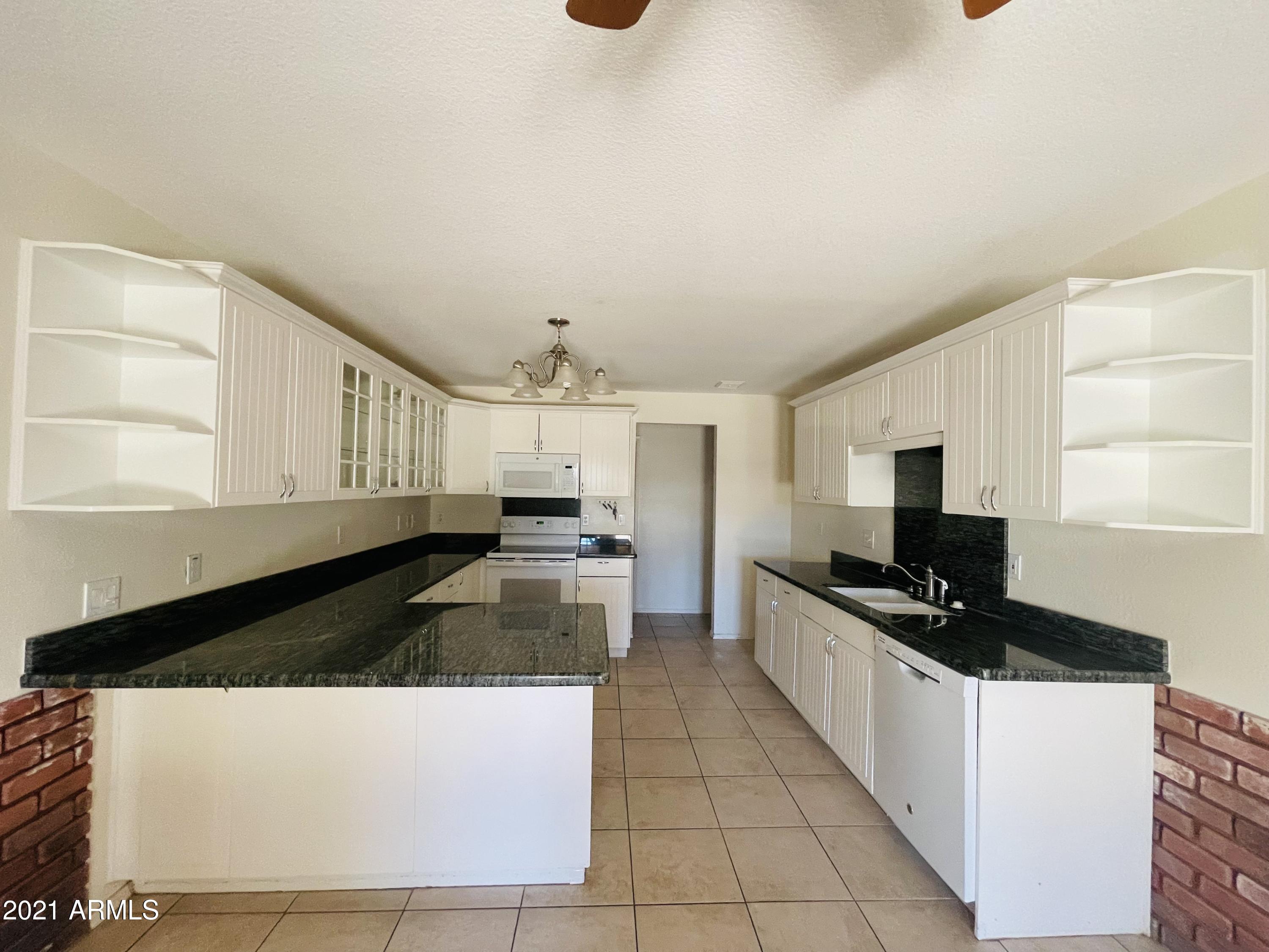 10642 East Arbor Avenue Mesa, AZ 85120 - Photo 3 of 12 a kitchen with granite countertop a sink a stove top oven a counter space and cabinets