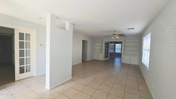 a view of a hallway with an empty room and a kitchen