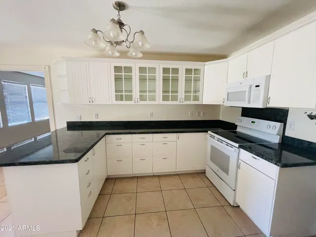 a kitchen with a sink dishwasher a stove and white cabinets with wooden floor