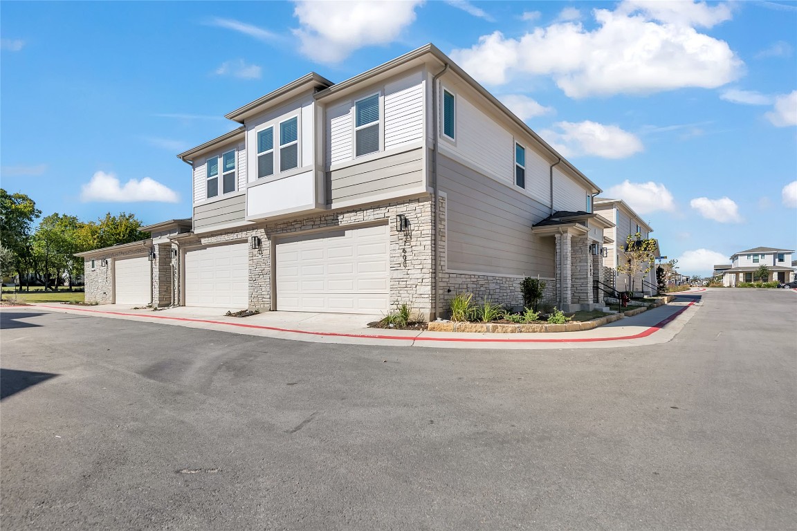 View of side of home featuring stone siding, an attached garage, and a residential view