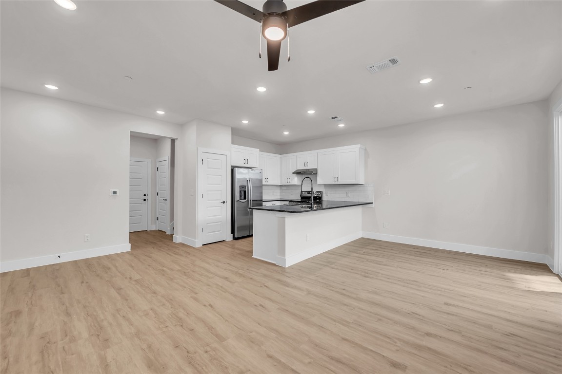 7600 Strong Bow Court Austin, TX 78744 - Photo 26 of 26 Kitchen featuring open floor plan, a peninsula, recessed lighting, white cabinets, and light wood-style floors