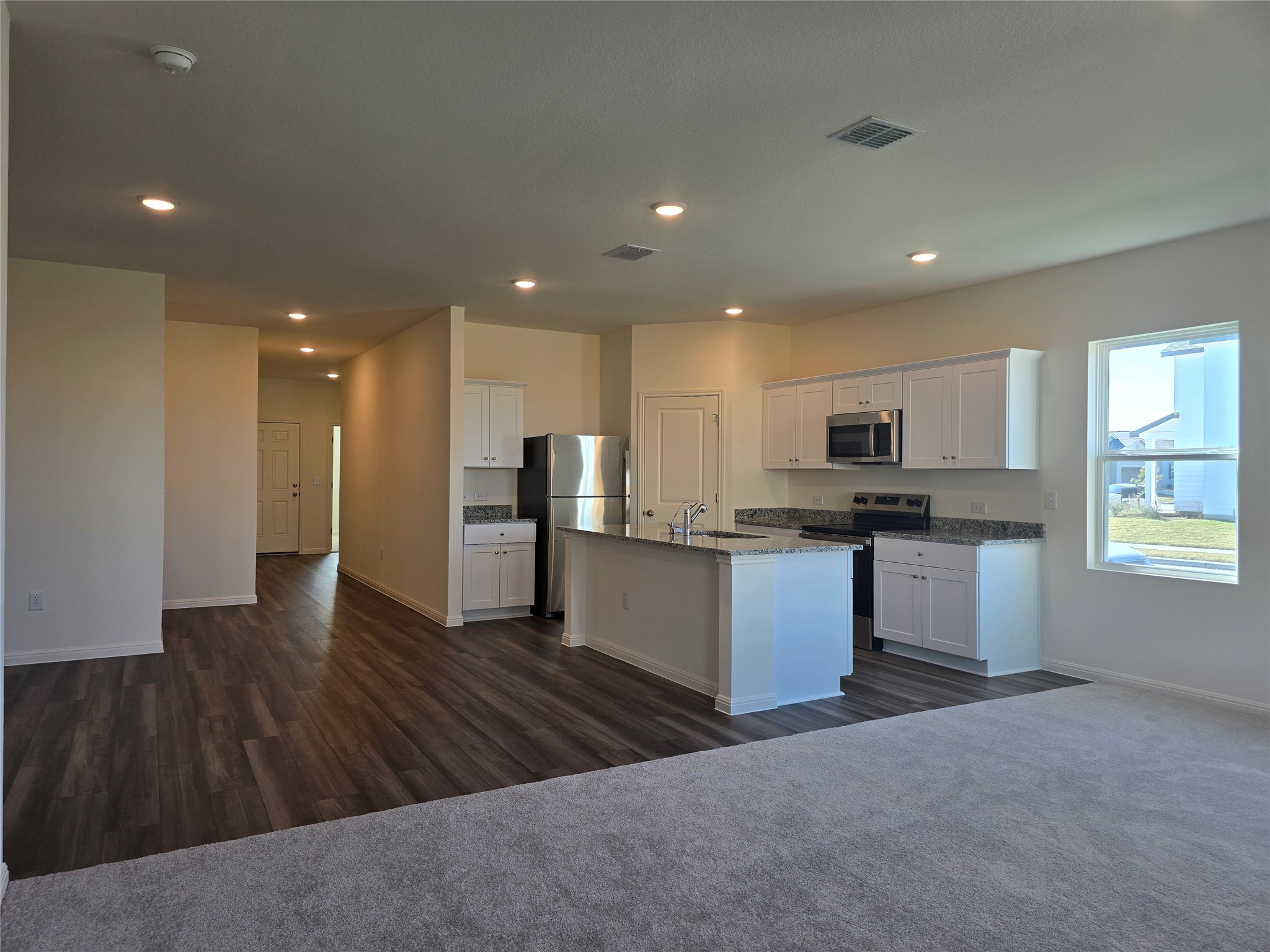 509 McFadin Way Taylor, TX 76574 - Photo 22 of 23 Kitchen with appliances with stainless steel finishes, white cabinets, open floor plan, recessed lighting, and dark carpet