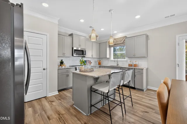 a kitchen with stainless steel appliances a refrigerator a stove a sink dishwasher and a refrigerator with wooden floor