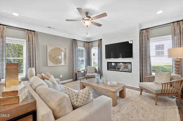 a living room with furniture a flat screen tv and a large window