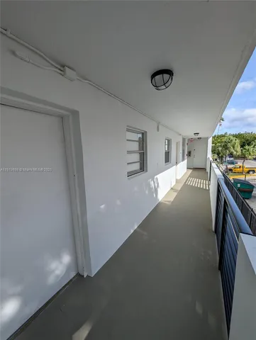 a view of a hallway to room with wooden floor and windows