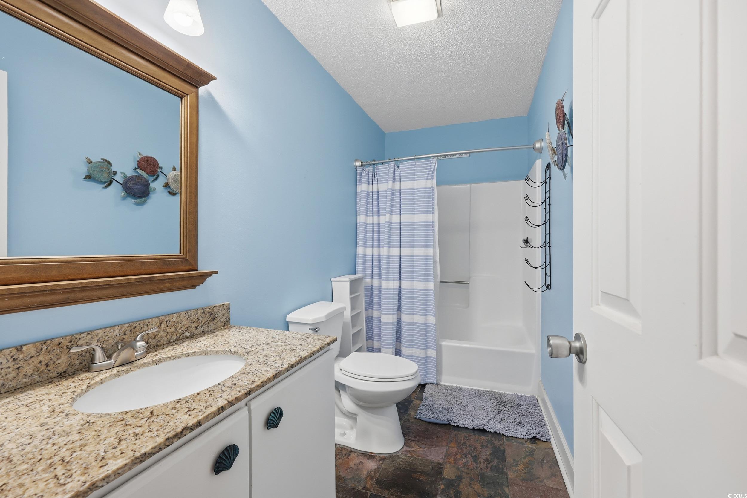 202 Double Eagle Drive, Unit C3 Surfside Beach, SC 29575 - Photo 12 of 20 Full bathroom featuring vanity, a textured ceiling, shower / bathtub combination with curtain, and stone finish flooring
