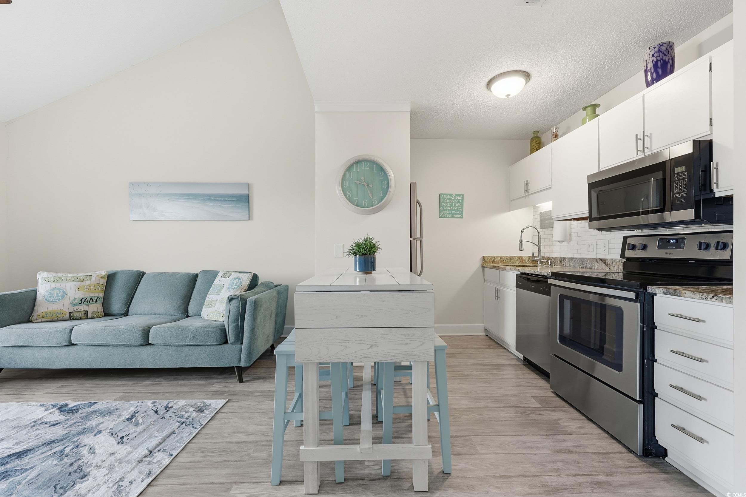 202 Double Eagle Drive, Unit C3 Surfside Beach, SC 29575 - Photo 19 of 20 Kitchen with stainless steel appliances, white cabinetry, decorative backsplash, open floor plan, and light wood finished floors