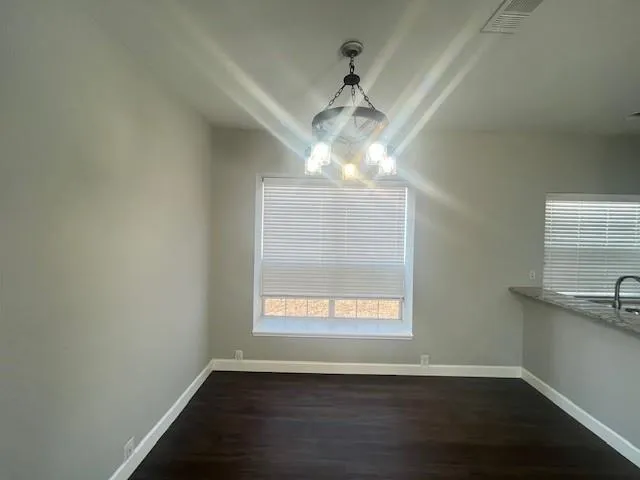 an empty room with wooden floor chandelier and window